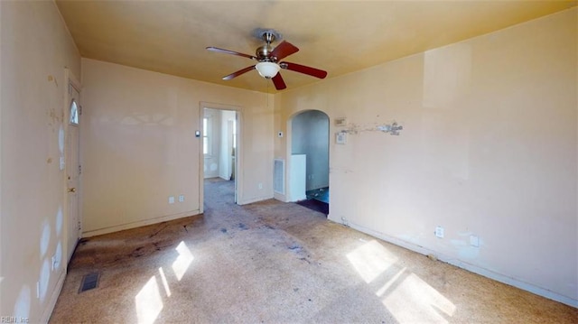 spare room featuring ceiling fan, visible vents, arched walkways, and baseboards