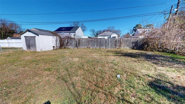 view of yard with a fenced backyard, an outdoor structure, and a storage unit