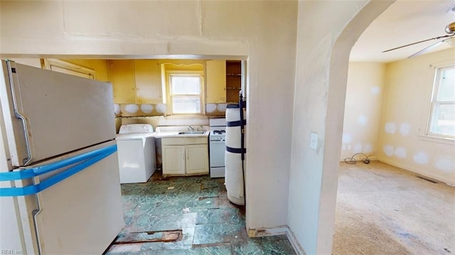 kitchen with white appliances, washer / dryer, visible vents, arched walkways, and light countertops