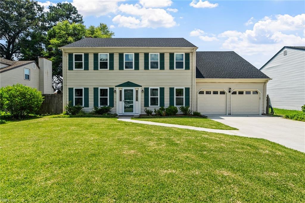 colonial-style house featuring a garage and a front lawn