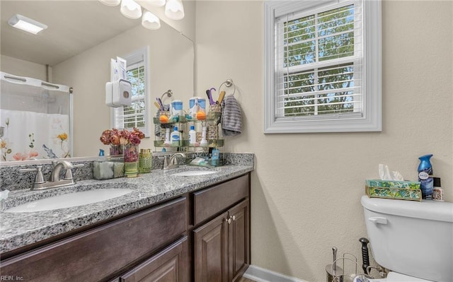 full bathroom featuring curtained shower, a sink, double vanity, and toilet