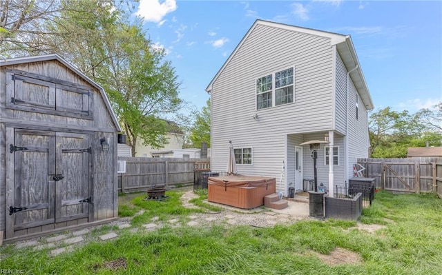 rear view of property with a fenced backyard, an outbuilding, a hot tub, and a yard