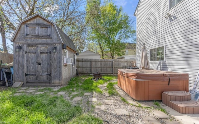 view of yard featuring a fenced backyard, a storage unit, a hot tub, and an outbuilding