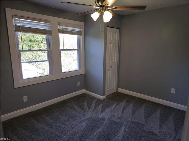 empty room with ceiling fan and dark colored carpet