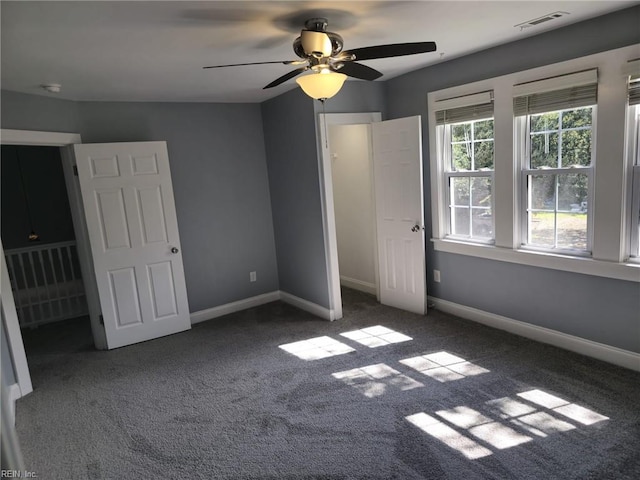 unfurnished bedroom with ceiling fan and dark colored carpet