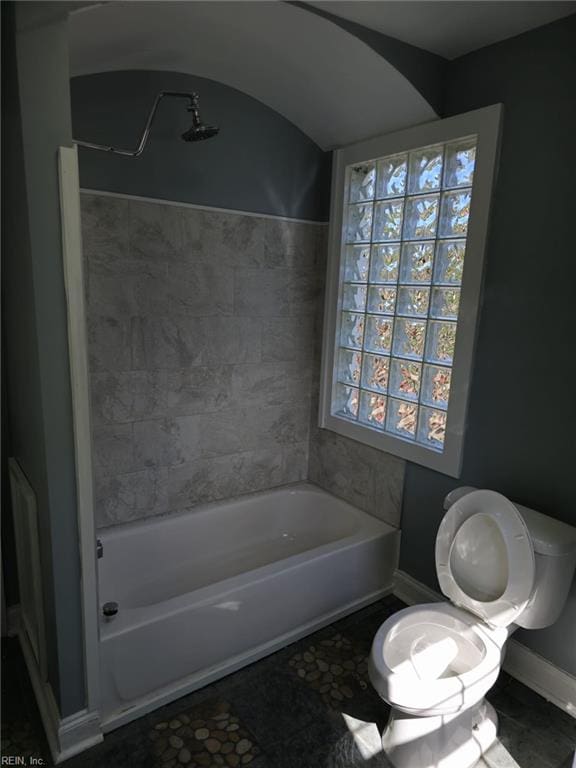 bathroom featuring tiled shower / bath combo and toilet