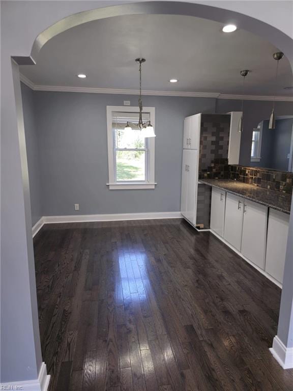 kitchen featuring pendant lighting, white cabinetry, dark hardwood / wood-style flooring, decorative backsplash, and ornamental molding