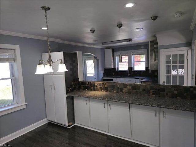 kitchen featuring white cabinetry, pendant lighting, decorative backsplash, and dark stone countertops