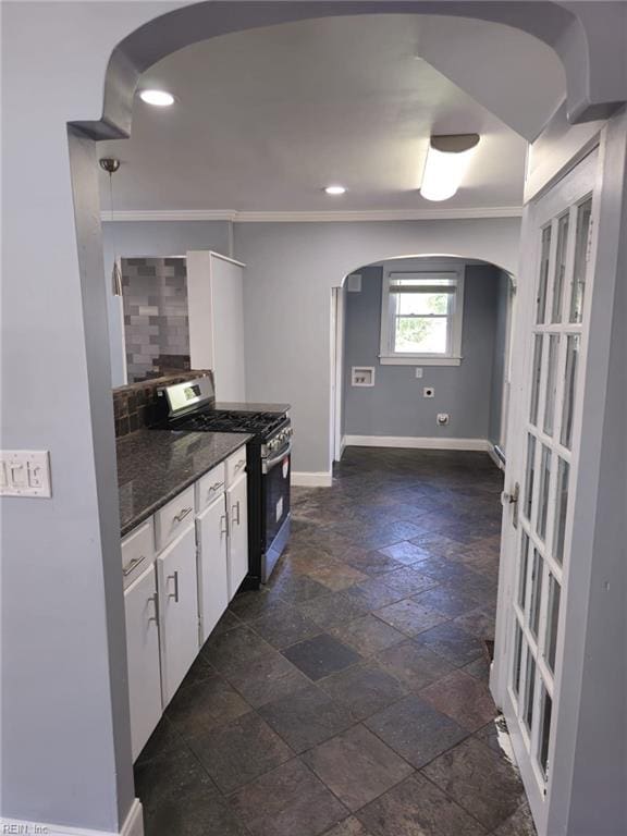 kitchen with crown molding, white cabinetry, decorative backsplash, stainless steel range with gas cooktop, and dark stone counters