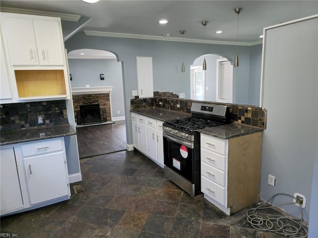 kitchen featuring dark stone countertops, backsplash, stainless steel range with gas cooktop, and white cabinets