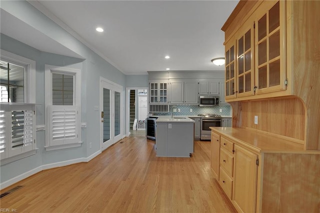 kitchen with backsplash, a center island, light hardwood / wood-style floors, stainless steel appliances, and crown molding