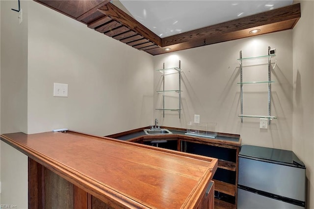 kitchen with stainless steel refrigerator, sink, and beam ceiling