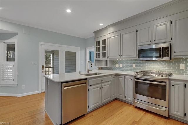 kitchen featuring light hardwood / wood-style flooring, stainless steel appliances, decorative backsplash, sink, and kitchen peninsula