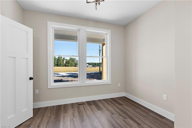 empty room with baseboards, visible vents, and dark wood-type flooring