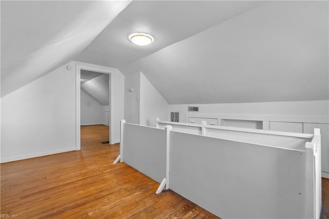 additional living space featuring vaulted ceiling and light wood-type flooring