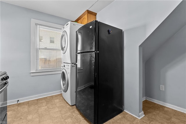 kitchen with black refrigerator, stacked washer and clothes dryer, and stove