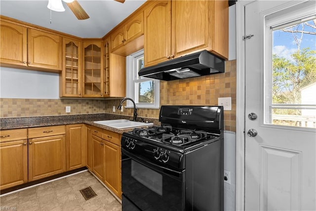 kitchen featuring sink, dark stone countertops, ceiling fan, black gas range, and backsplash