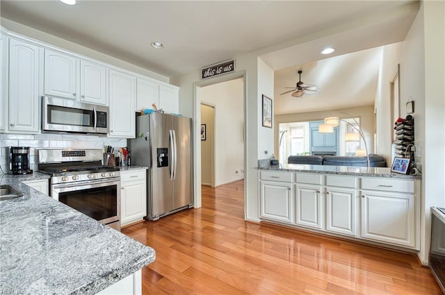 kitchen featuring stainless steel appliances, light stone countertops, and white cabinets