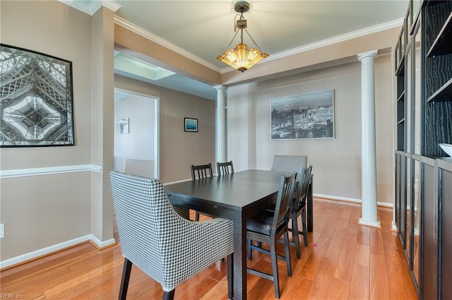 dining room featuring light hardwood / wood-style floors, crown molding, and decorative columns