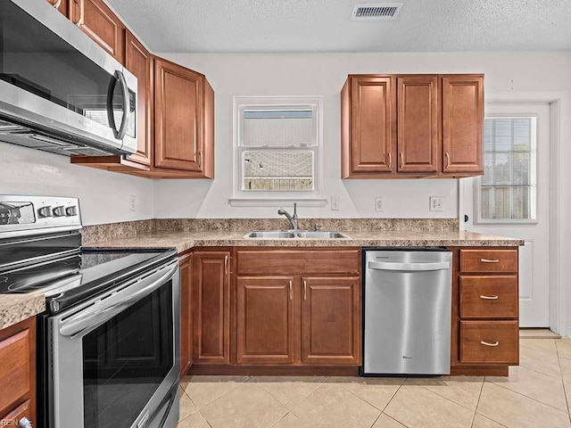 kitchen featuring sink, a textured ceiling, stainless steel appliances, and light tile patterned floors