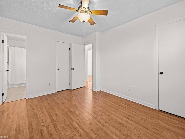 unfurnished bedroom with light hardwood / wood-style flooring, a textured ceiling, and connected bathroom