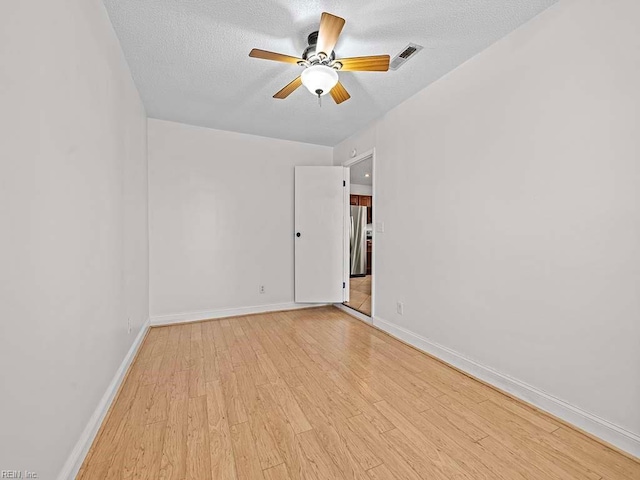 unfurnished room with ceiling fan, light hardwood / wood-style floors, and a textured ceiling