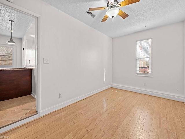 empty room featuring a textured ceiling, ceiling fan, and light hardwood / wood-style floors