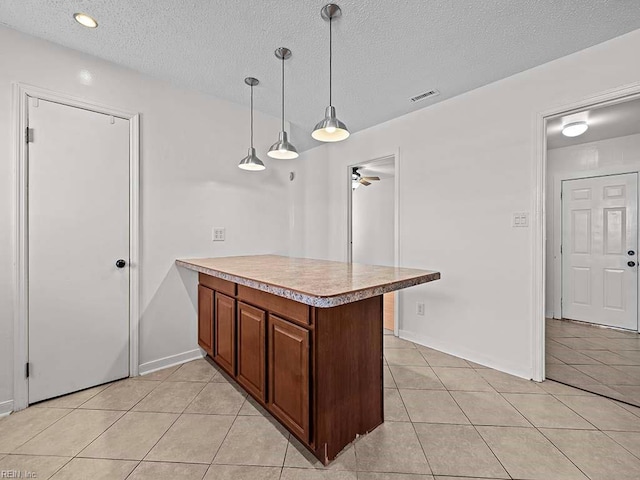 kitchen with hanging light fixtures, light tile patterned floors, a textured ceiling, and kitchen peninsula