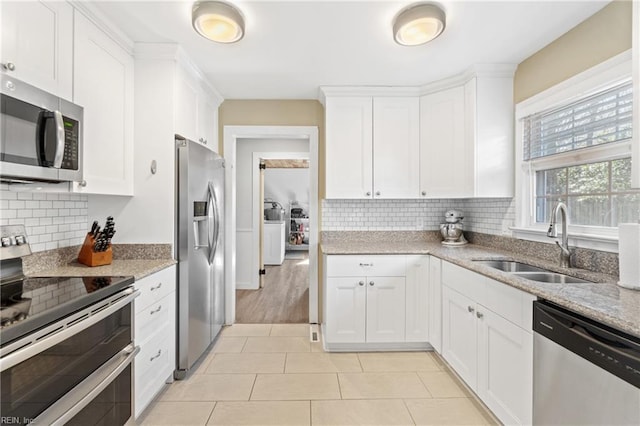 kitchen featuring appliances with stainless steel finishes, a sink, white cabinetry, and light stone countertops