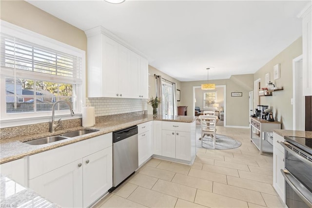 kitchen with tasteful backsplash, appliances with stainless steel finishes, white cabinetry, a sink, and light stone countertops