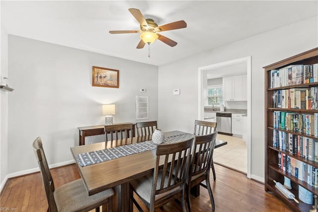 dining space with a ceiling fan, baseboards, and light wood finished floors