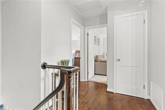 corridor with dark wood-style flooring, an upstairs landing, and visible vents