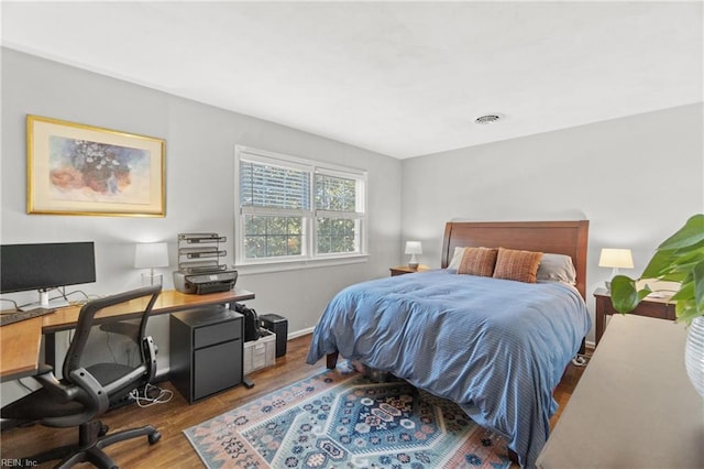 bedroom with baseboards, visible vents, and wood finished floors