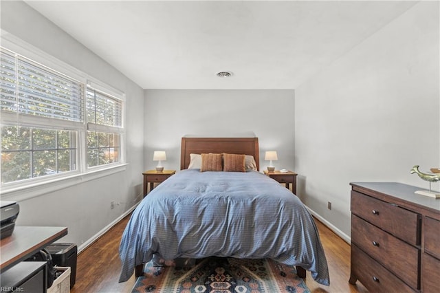 bedroom with wood finished floors, visible vents, and baseboards