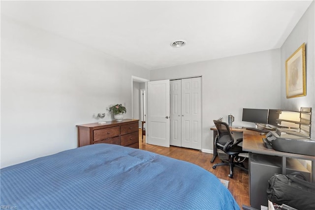 bedroom featuring baseboards, a closet, visible vents, and wood finished floors