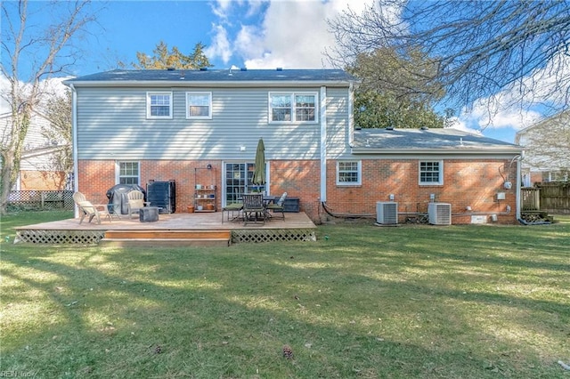 rear view of property with central air condition unit, a yard, and brick siding