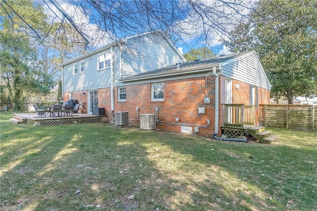 back of house featuring a lawn, fence, a wooden deck, central air condition unit, and brick siding