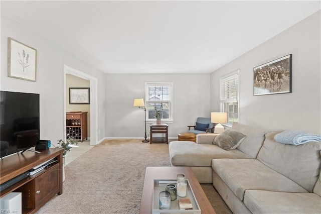 living area featuring light carpet and baseboards