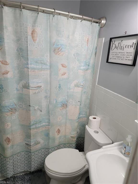 bathroom featuring tile walls and toilet