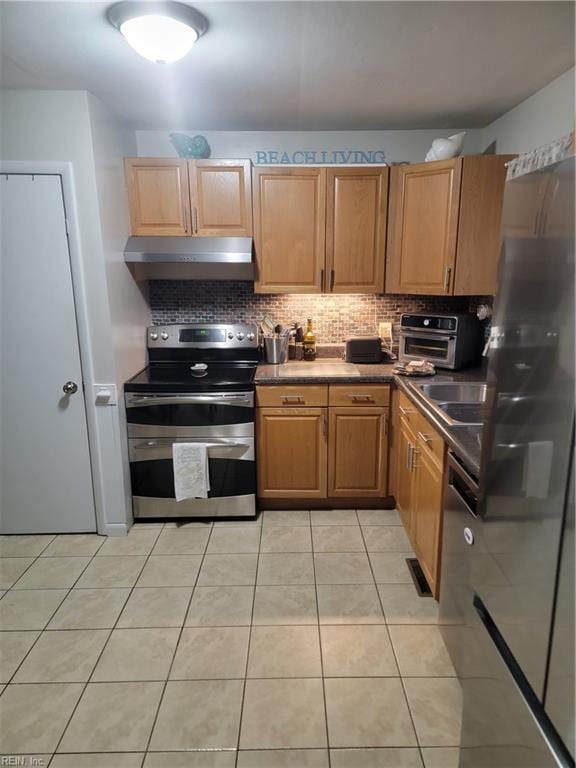 kitchen featuring decorative backsplash, range with two ovens, and light tile patterned floors