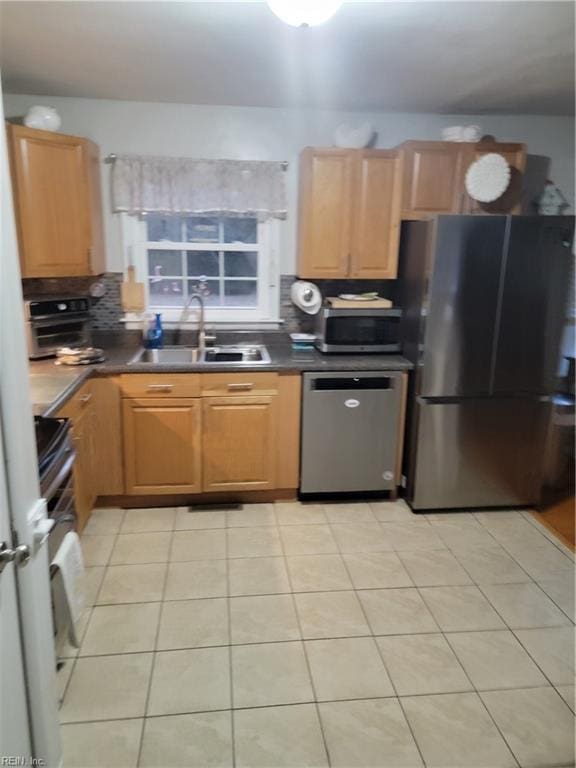 kitchen with appliances with stainless steel finishes, sink, light tile patterned floors, and decorative backsplash