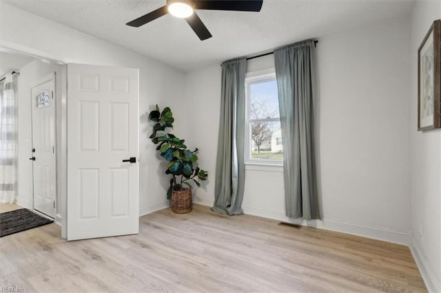 interior space with light hardwood / wood-style floors, vaulted ceiling, ceiling fan, and a textured ceiling