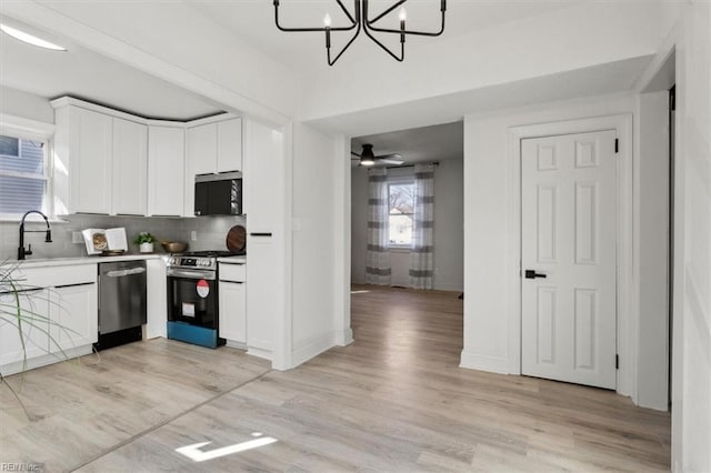 kitchen with sink, backsplash, white cabinets, and stainless steel appliances