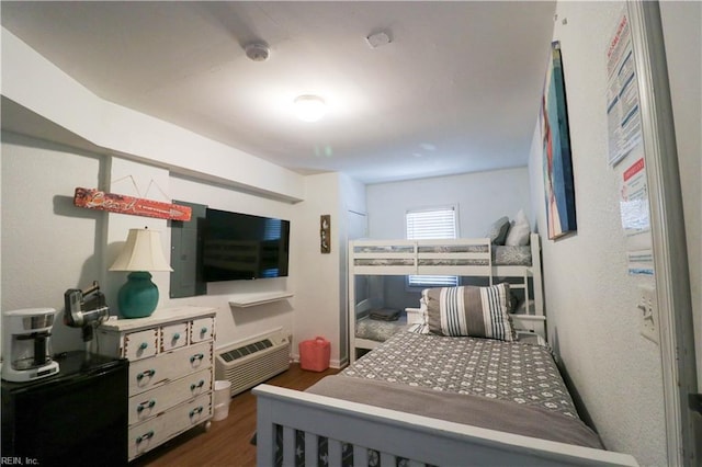 bedroom with an AC wall unit and dark hardwood / wood-style floors