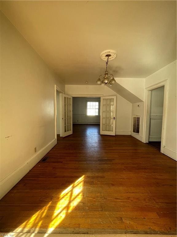 unfurnished living room featuring a notable chandelier and dark hardwood / wood-style floors