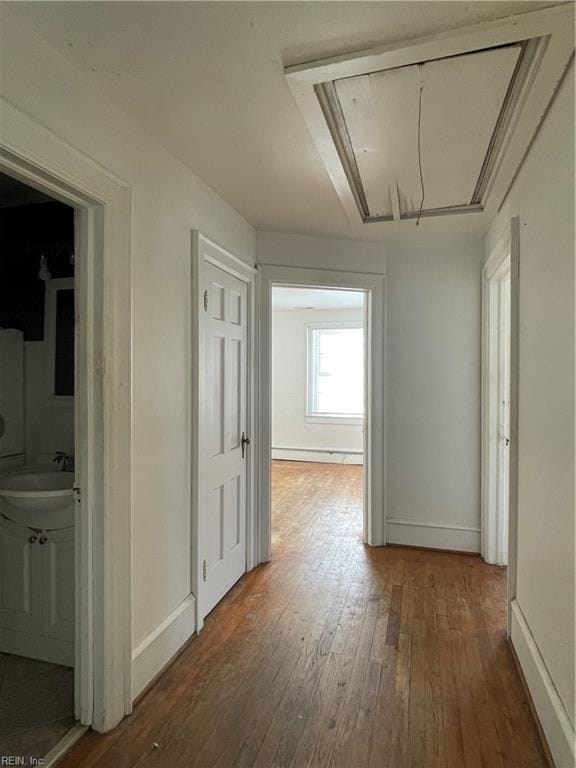 hallway featuring sink, dark wood-type flooring, and a baseboard heating unit