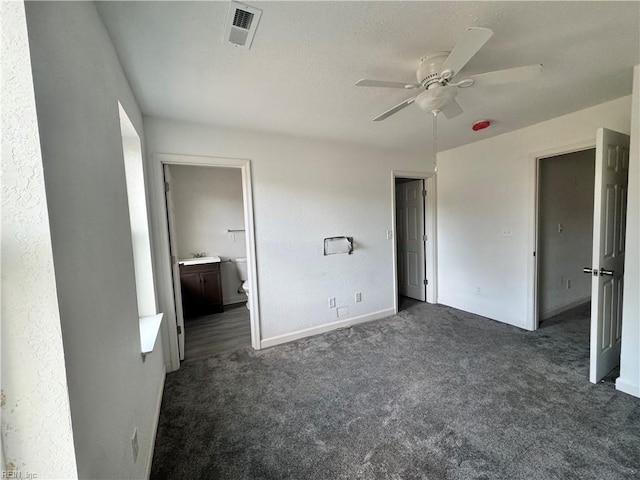 unfurnished bedroom with sink, dark colored carpet, connected bathroom, and ceiling fan