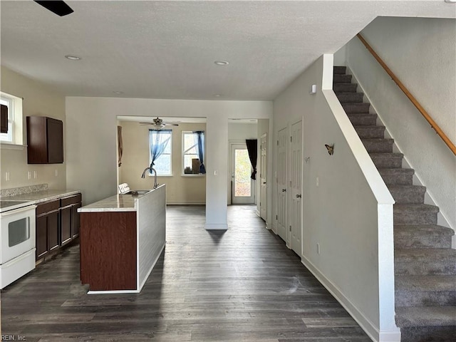 kitchen featuring a kitchen island with sink, dark hardwood / wood-style flooring, dark brown cabinetry, white range with electric cooktop, and ceiling fan