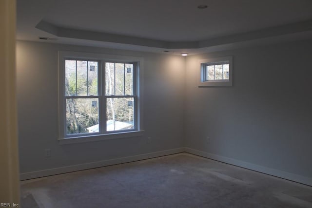 spare room with a tray ceiling and concrete floors