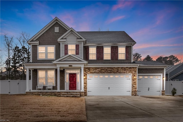 view of front of home featuring stone siding, a gate, driveway, and fence